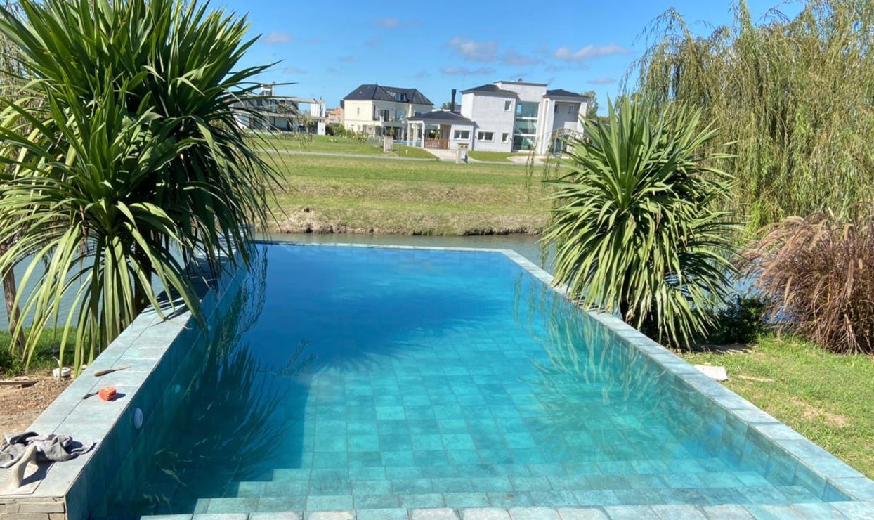 Piscina revestida en Piedra Bali con tonalidades turquesa, Haras del Sur 2