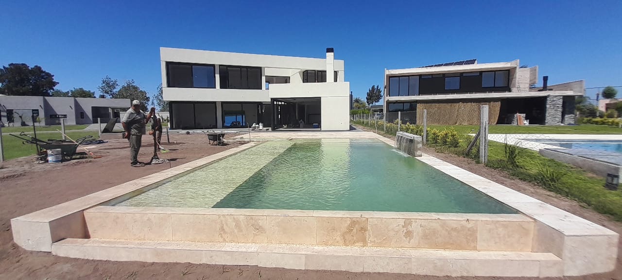 Piscina premium en mármol travertino con hidromasaje y borde infinito, Haras del Sur 2