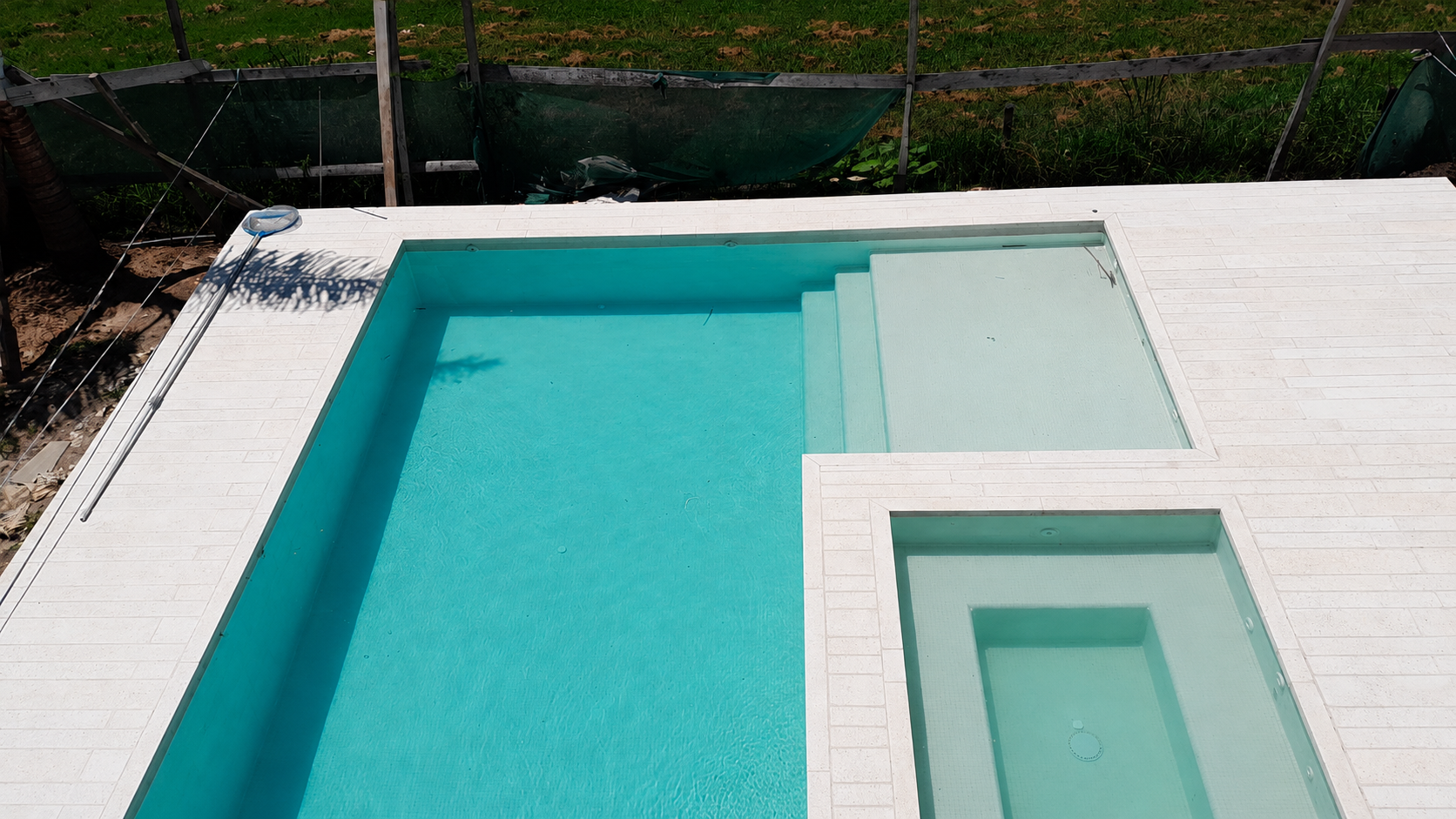 Piscina con playa húmeda en L y jacuzzi con hidrojets, diseño minimalista